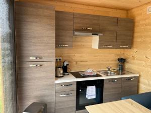 uma pequena cozinha com armários de madeira e um lavatório em Le Laponya - Chalet climatisé avec SPA & Borne de recharge em Bressols