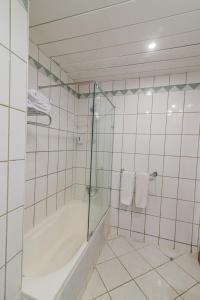 Dexon Roma Hotel في الغردقة: حمام ذو بلاط أبيض مع دش وحوض استحمام