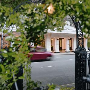 una macchina rossa che guida lungo una strada di fronte a un edificio di Hyatt Regency London - The Churchill a Londra