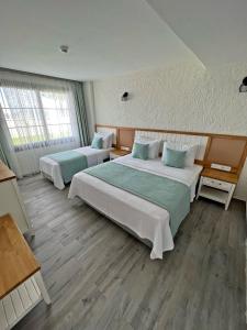 a hotel room with two beds and two windows at Vahide Dalyan in Çeşme