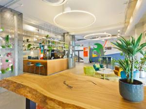 a lobby with a wooden counter with a potted plant at IBIS Styles Kaunas Centre in Kaunas