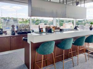 a kitchen with a counter with green stools at IBIS Styles Kaunas Centre in Kaunas