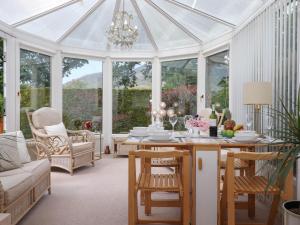 a conservatory with a table and chairs and a chandelier at Oaklea in Keswick