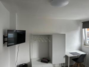 een kamer met een tv aan de muur en een bureau bij Quins in Aalen