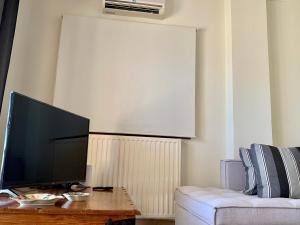 uma sala de estar com uma televisão de ecrã plano e um sofá em Aggelos and Thisbe Chania Suburbs Sea View Guest House em Chania