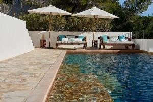 een zwembad met 2 stoelen en 2 parasols bij Villa Larosa with seaview in Es Cubells Ibiza in Es Cubells