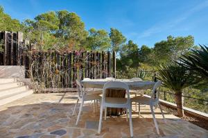 een tafel en stoelen op een patio met een hek bij Villa Larosa with seaview in Es Cubells Ibiza in Es Cubells