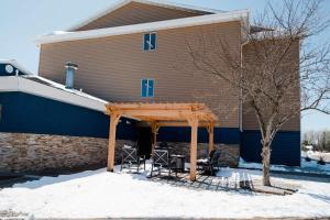 een huis met een prieel en stoelen in de sneeuw bij AmericInn by Wyndham Tomahawk in Tomahawk