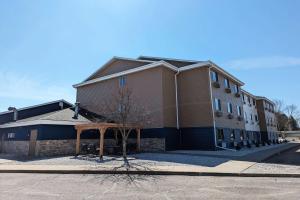 a building with a tree in front of it at AmericInn by Wyndham Tomahawk in Tomahawk