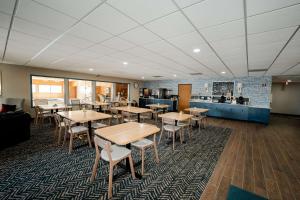 a dining room with tables and chairs and a kitchen at AmericInn by Wyndham Tomahawk in Tomahawk