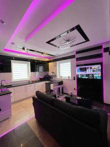 a living room with a couch and a kitchen with purple lights at #2 TGHA Luxury Studio Apartment in Athlone in Athlone
