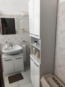 a white bathroom with a sink and a mirror at Panoráma apartman in Pécs