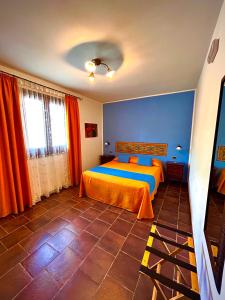a bedroom with a bed with orange sheets and blue walls at B&B L'Angolino della nonna in Castelluzzo