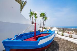 niebieska i czerwona łódź siedząca na boku budynku w obiekcie Sun Angelos Oia - Luxury Cave Suites w mieście Oia
