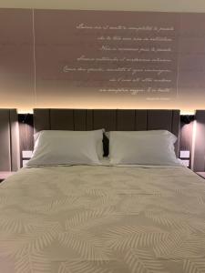 a bed with white pillows and a wall with writing on it at Donna Caterina in Monopoli
