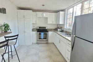 a kitchen with white cabinets and a stainless steel refrigerator at De Terrace #2 in Christ Church