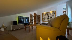 un salon avec une chaise jaune et une télévision dans l'établissement Mavericklodge, à LʼAquila