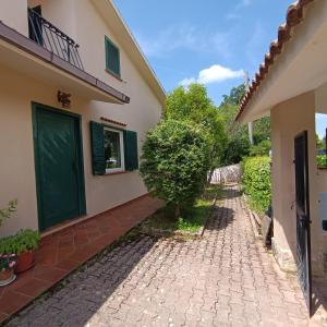 a house with a green door and a brick walkway at Moon Ash - Cenere di Luna in Poggio Moiano