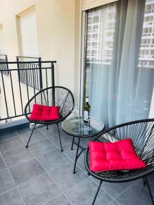 a balcony with two chairs and a table with red pillows at StayPoint Apartment in Podgorica