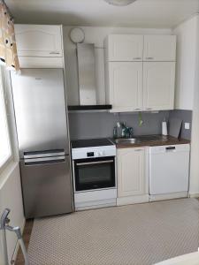uma cozinha com armários brancos e um frigorífico de aço inoxidável em Kempele city center em Kempele