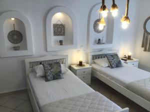 two beds in a room with white walls and lights at Francesca Secret in Mikonos