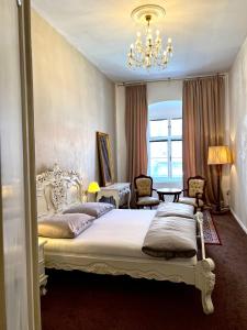 a bedroom with a large white bed and a chandelier at Csaky Palace Bratislava in Bratislava