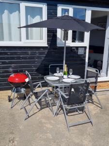 einen Tisch und Stühle mit einem Sonnenschirm und einem Grill in der Unterkunft The Old Workshop Oxford Countryside Apartment - Wifi - Free Parking in Oxford