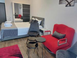um quarto com uma cama e uma cadeira vermelha em Garsoniera Carmina em Techirghiol
