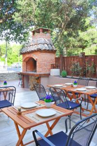 a patio with wooden tables and chairs and a brick oven at Apartments Katušić in Cavtat