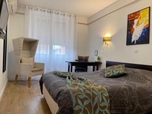 a bedroom with a bed and a chair and a desk at L'EMBLEME - BOUTIQUE HOTEL in Beaurepaire