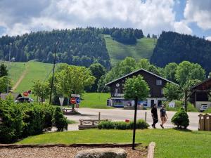 paru ludzi idących drogą przed domem w obiekcie Place Royale pour 10 à 12 personnes à 30 mèt des pistes de Ski et Vtt w mieście Métabief