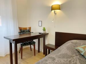 einen Schreibtisch in einem Hotelzimmer mit einem Bett, einem Tisch und einem Stuhl in der Unterkunft L'EMBLEME - BOUTIQUE HOTEL in Beaurepaire