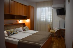 um quarto com uma cama, uma secretária e uma televisão em Guest house Tom em Malinska