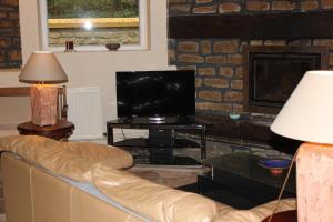ein Wohnzimmer mit einem Sofa und einem TV in der Unterkunft Le Moulin in Matton-et-Clémency