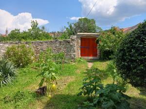 eine Scheune mit einer roten Tür im Garten in der Unterkunft Makina in Nerežišće