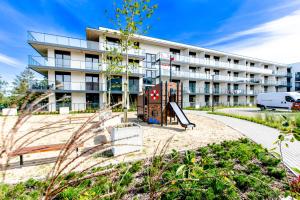 Un edificio de apartamentos con un parque infantil enfrente. en Apartament RiverView Bridge Apartments & Spa Dziwnów Epapartamenty, en Dziwnów