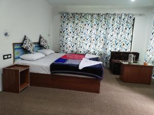 a bedroom with a bed and a chair and a window at Tip Top Pahalgam in Pahalgām