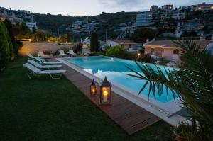 a backyard with a swimming pool with lights and chairs at Villa Marina, Sea View Luxury Villa in Mati
