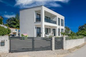 a white house with a wooden fence at Villa Alma Krk in Krk