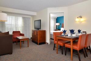 オーロラにあるResidence Inn by Marriott Denver Airport at Gateway Parkのダイニングテーブルとベッドルームが備わるホテルルームです。