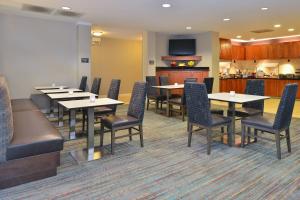 a dining room with tables and chairs and a kitchen at Residence Inn by Marriott Denver Airport at Gateway Park in Aurora