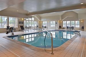 uma piscina no átrio do hotel com mesas e cadeiras em Residence Inn by Marriott Denver Airport at Gateway Park em Aurora