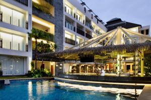 a hotel with a swimming pool in front of a building at Fairfield by Marriott Bali Legian in Legian