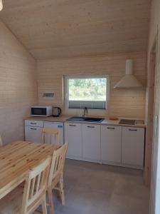 a kitchen with white cabinets and a table and a window at Zante Sarbinowo in Sarbinowo
