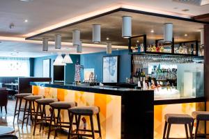 a bar in a restaurant with stools at AC Hotel by Marriott Birmingham in Birmingham