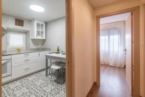 una cucina con armadi bianchi, tavolo e scrivania di Pría, apartamento en Ribadesella a Ribadesella