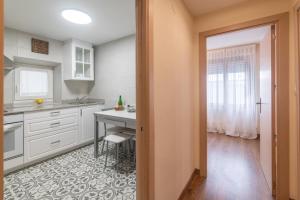 a kitchen with white cabinets and a table and a desk at Pría, apartamento en Ribadesella in Ribadesella