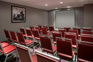 een conferentieruimte met rode stoelen en een scherm bij Four Points by Sheraton Boston Logan Airport Revere in Revere