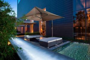 a pool with a table and an umbrella and a couch at The Westin Guadalajara in Guadalajara