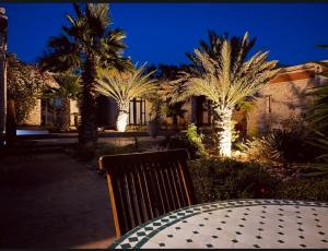 Villa des Hauts Mogador في الصويرة: طاولة مع مقاعد و نخيل في الليل